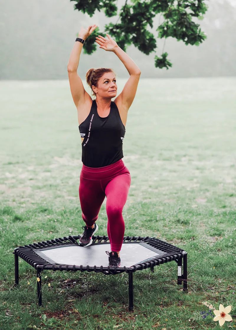 Anna na mini trampolinie na świeżym powietrzu, z uniesionymi rękami