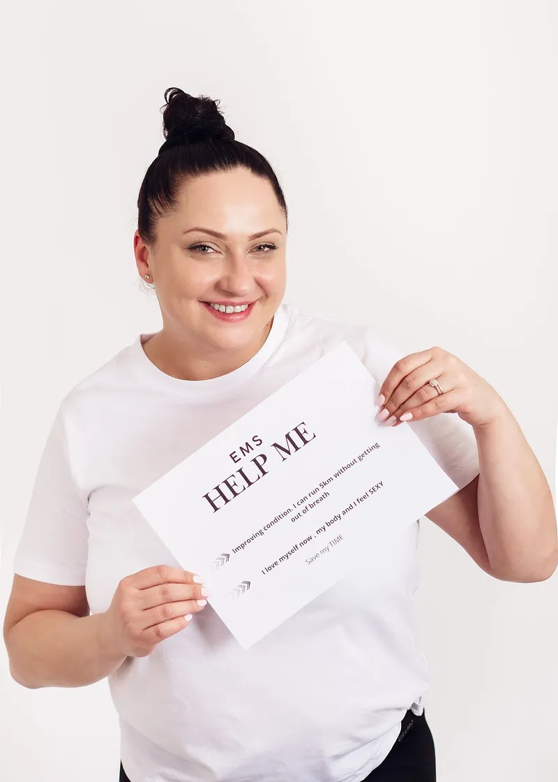 A smiling client holds up a card headed EMS Help Me