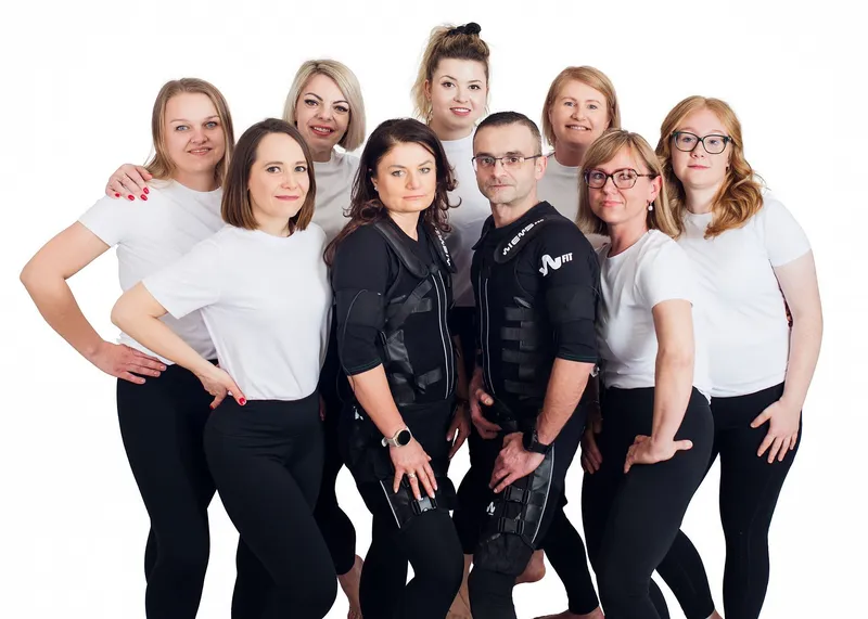 Anna i Rafal w czarnych kombinezonach EMS wśród klientek Smart Body Studio w białych koszulkach